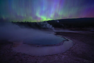 Crested Pool reflects the sky and colors from an aurora in Yellowstone.