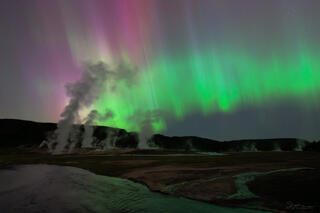 A sky with aurora over the Firehole River and Biscuit Basin in Yellowstone National Park.