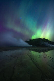 The aurora dances in the sky above Excelsior Geyser Crater in Yellowstone.