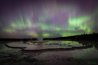 Aurora reflects in the terraces of Great Fountain Geyser in Yellowstone.