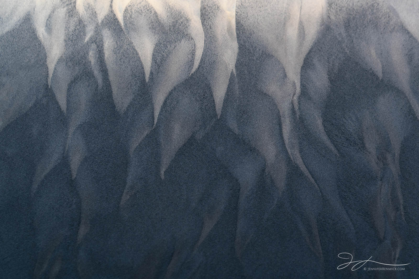 Sand patterns left after a retreating wave create ghostly shapes.