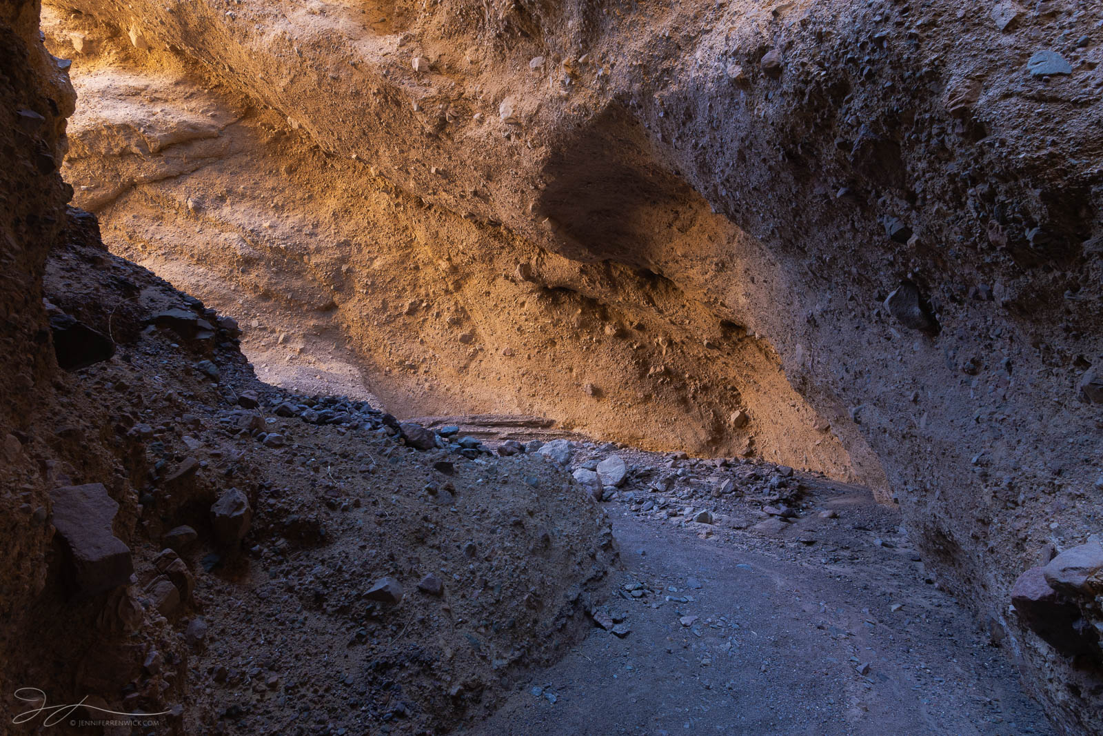 Light glows on the walls of a remote slot canyon in the desert.