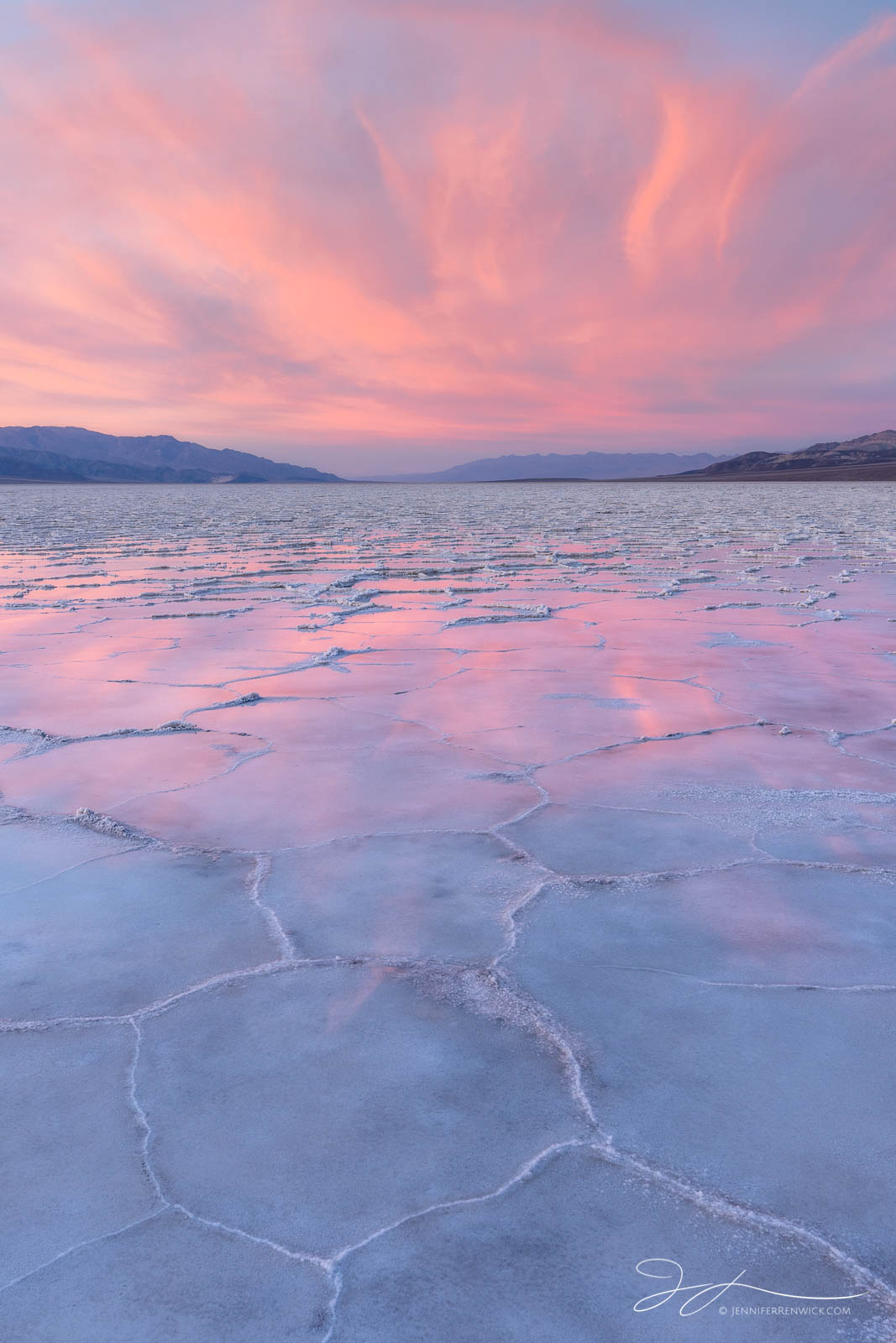 A pink sunset reflects onto a partially flooded Badwater Basin in Death Valley National Park.