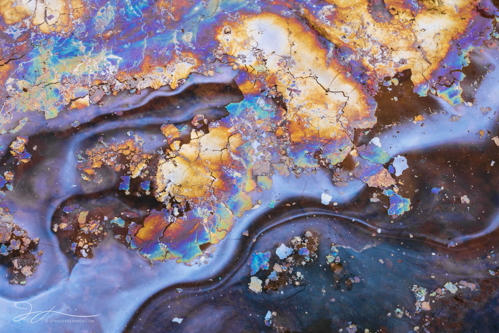 A patch of natural oils is disturbed and broken from a flow of water.