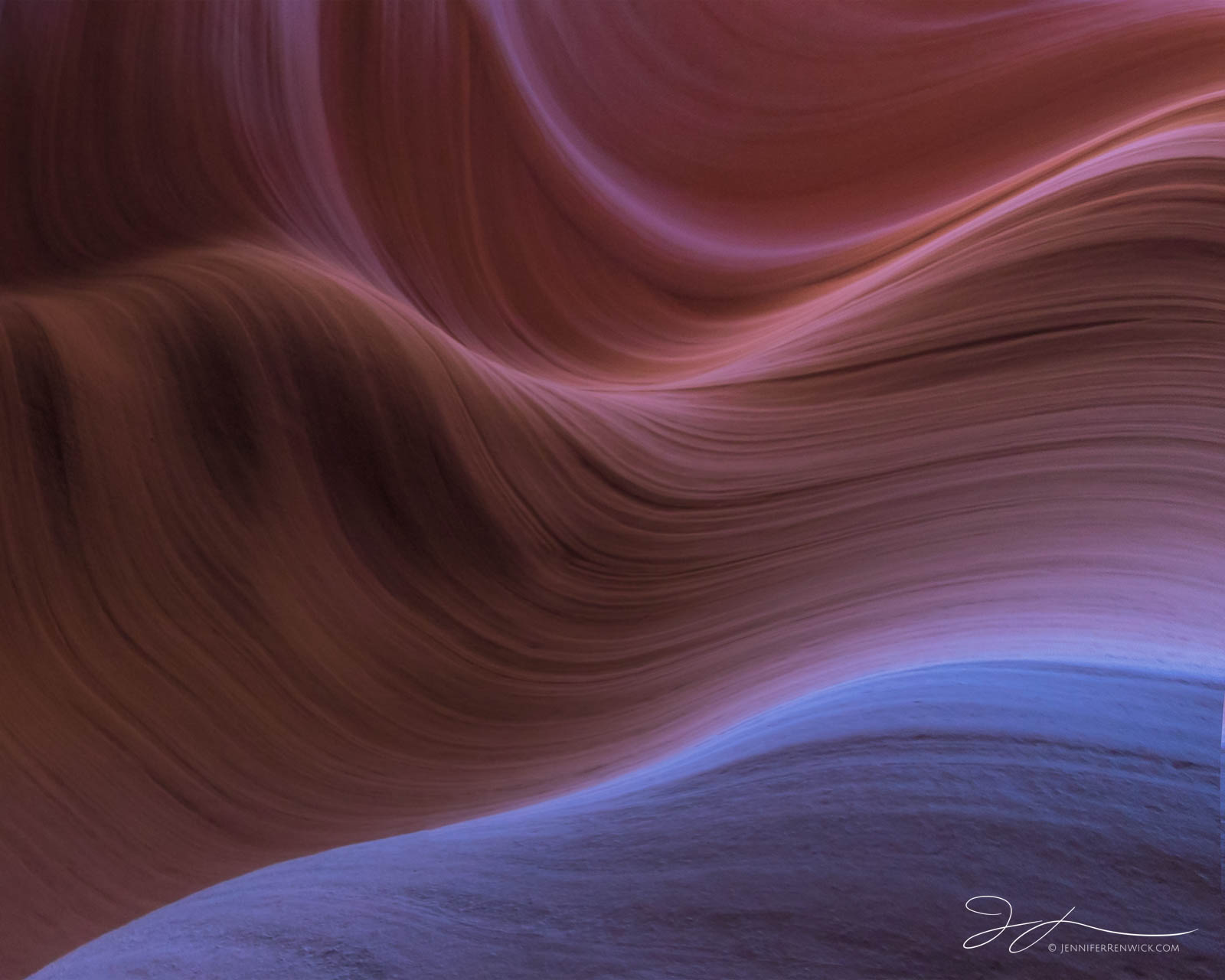 Smooth ridges reflect the blue in the sky and reflected warm light in a slot canyon.