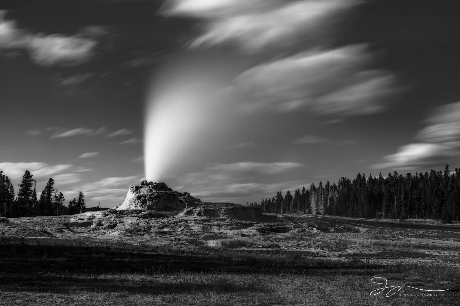 Castle Geyser erupts on a partly cloudy day in the Upper Geyser Basin. This image was photographed using a longer exposure to...