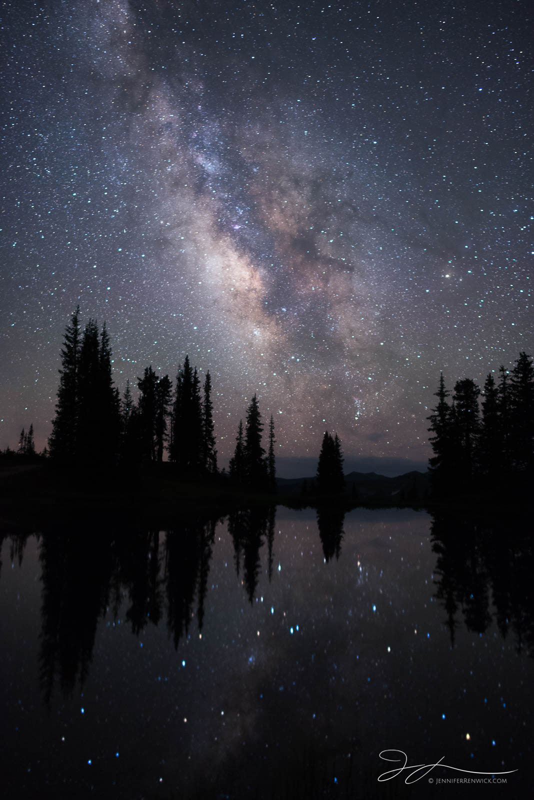 The Milky Way rises in the summer night sky above an alpine pond.