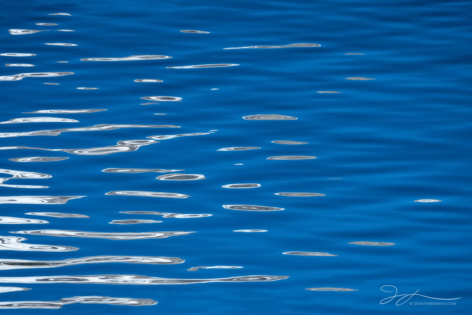 Clouds and sky reflect in Jenny Lake, creating an abstract look on the water's surface.