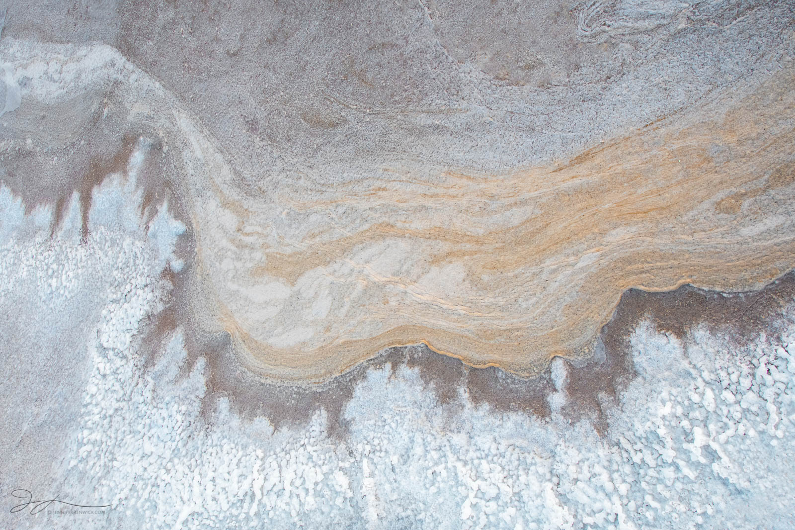 Deposits on the desert floor resemble a seashore with an incoming "wave."
