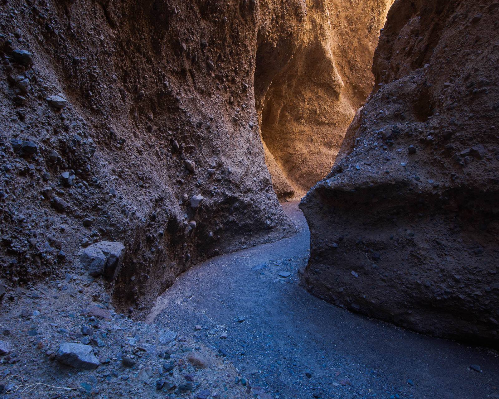 Cool shadows and warm reflected light lead the way through a remote slot canyon in Death Valley National Park.