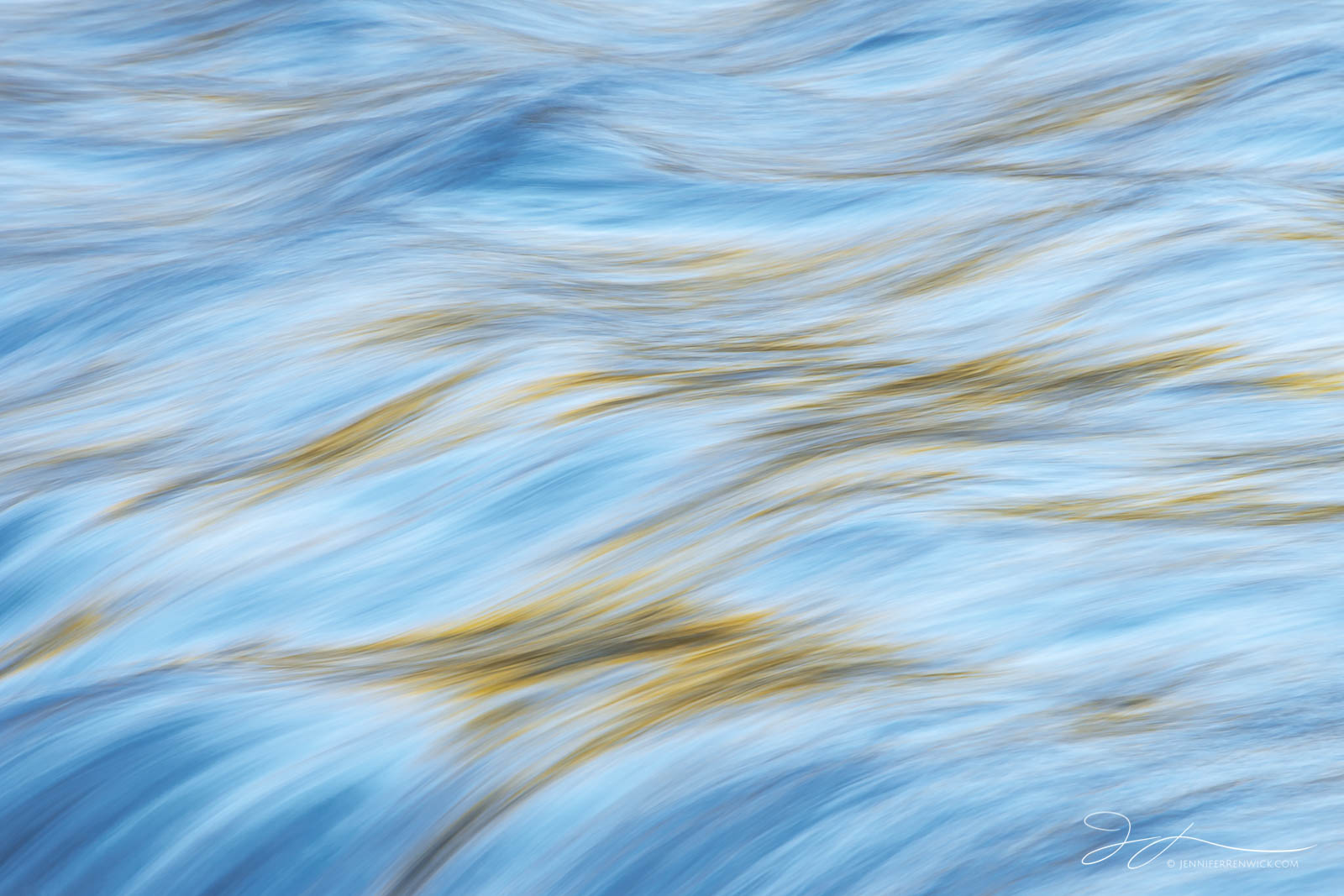 Trees catching the last sunlight of the day cast reflected light onto a set of small rapids in Yellowstone National Park. This...