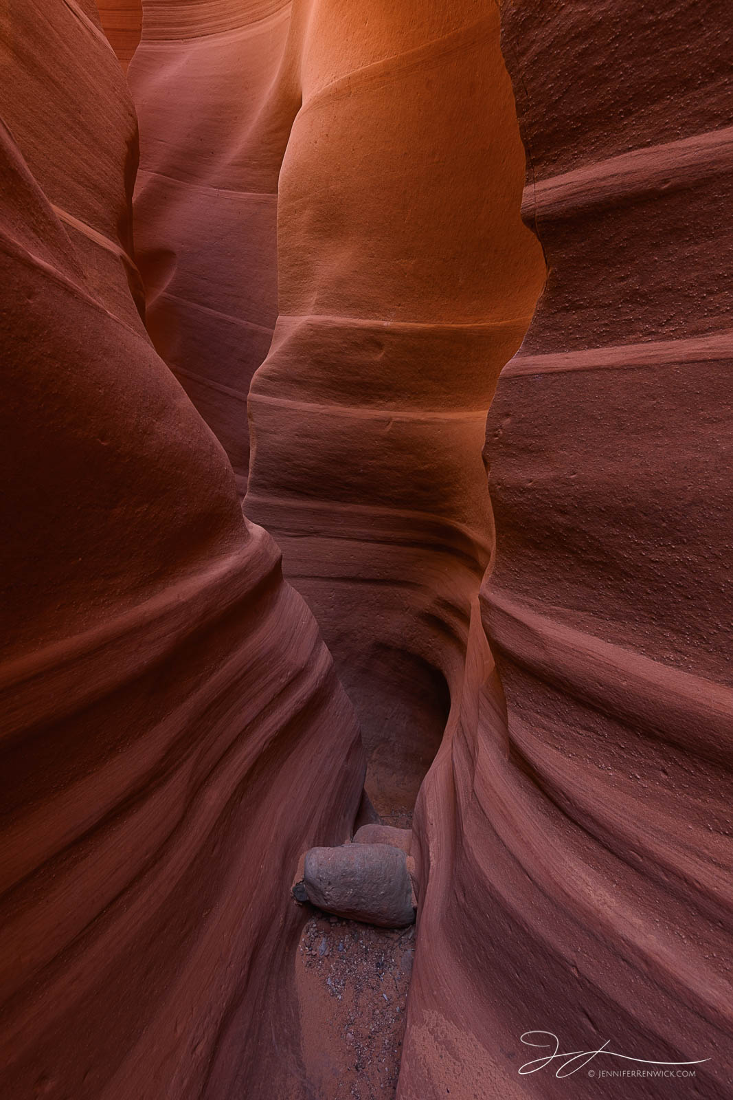 Warm light glows along the walls of a slot canyon, creating warmth from within.