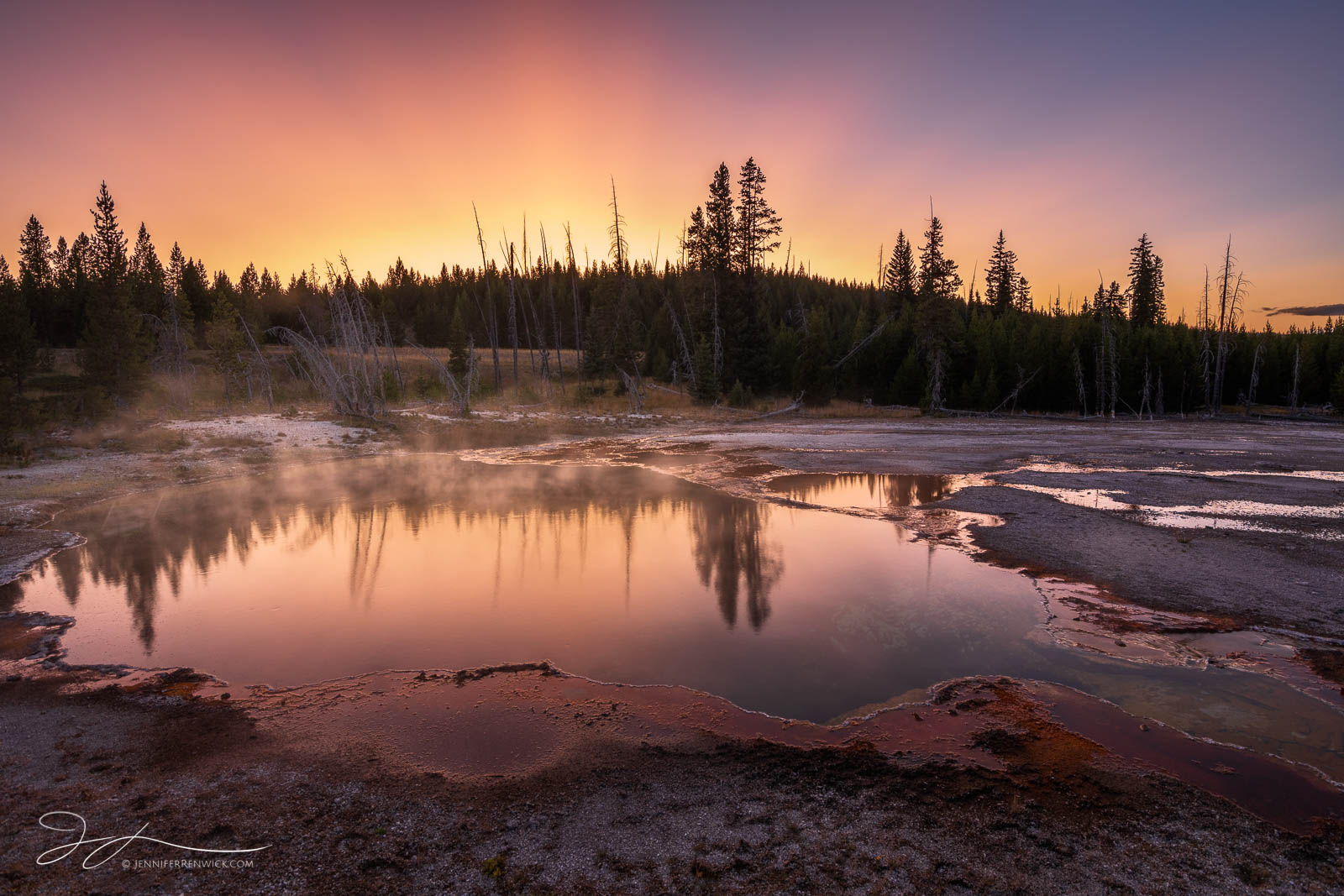 Sunset colors light up the sky and reflect into the Abyss Pool in West Thumb Geyser Basin.