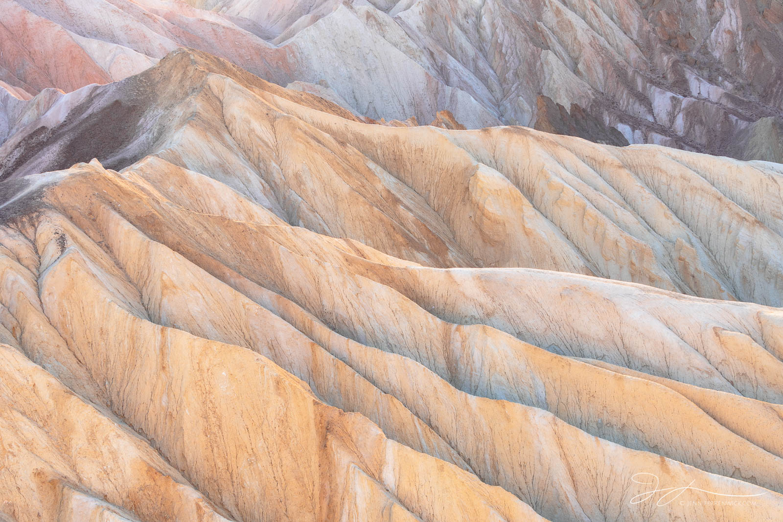 Layers and ridges in the badlands glow under the last light of the day.