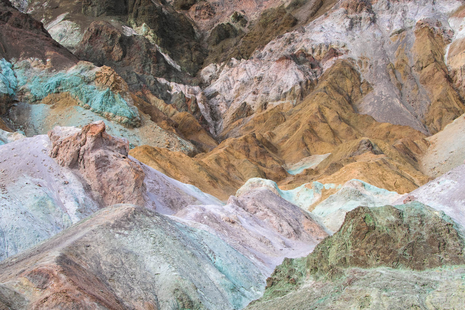 Colorful badlands in pastels of pink, green and brown glow in soft light.