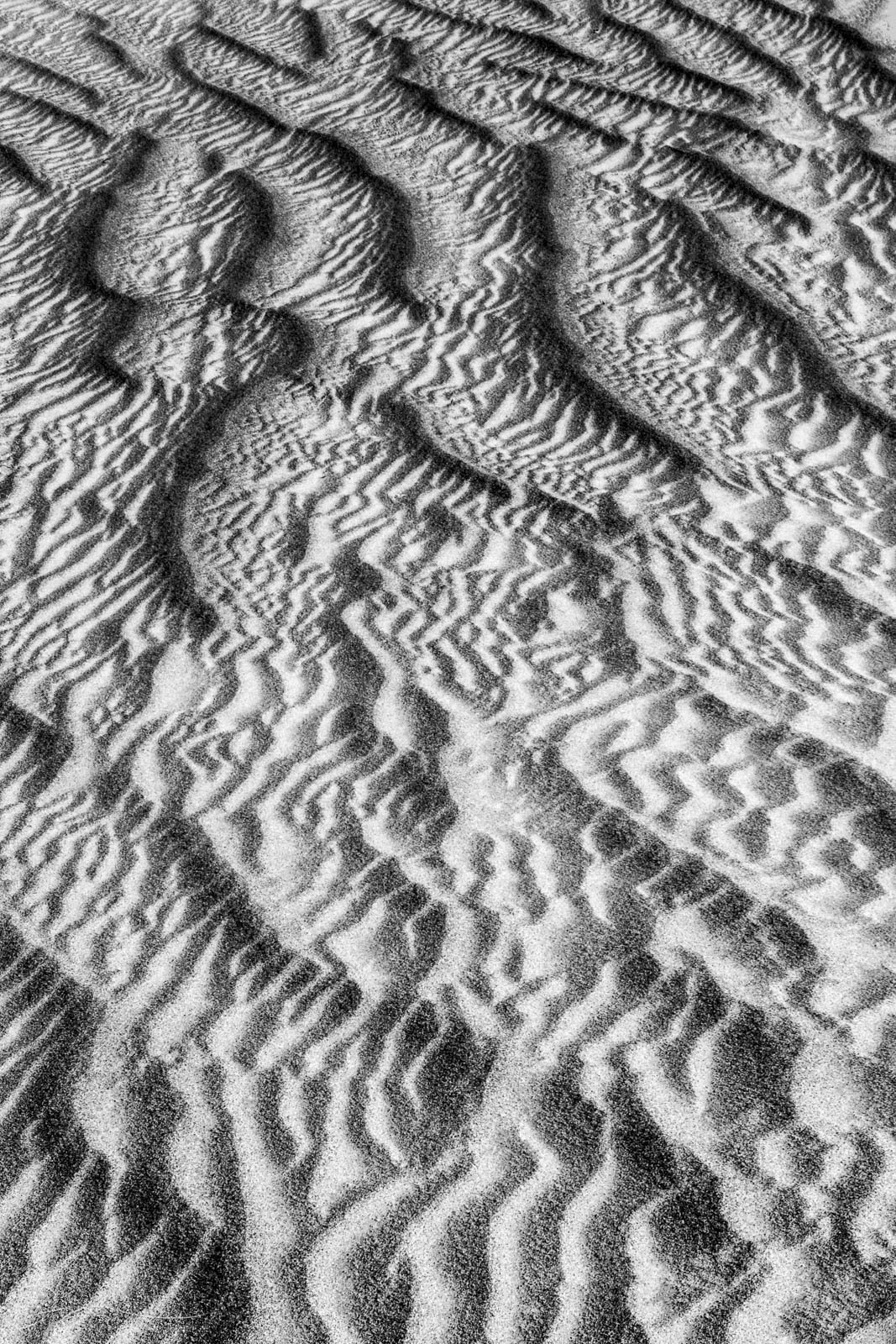 Sand patterns resemble aerial badlands on the desert floor.