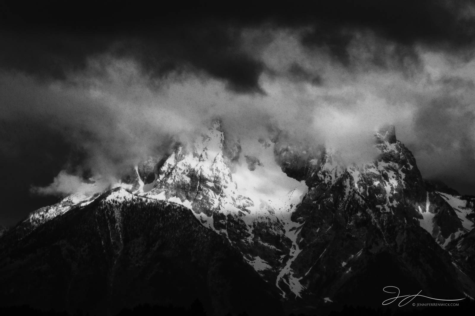 Mount Moran stands among low clouds and flying snowflakes during a summer snowstorm. If you look closely, you can see the snowflakes...