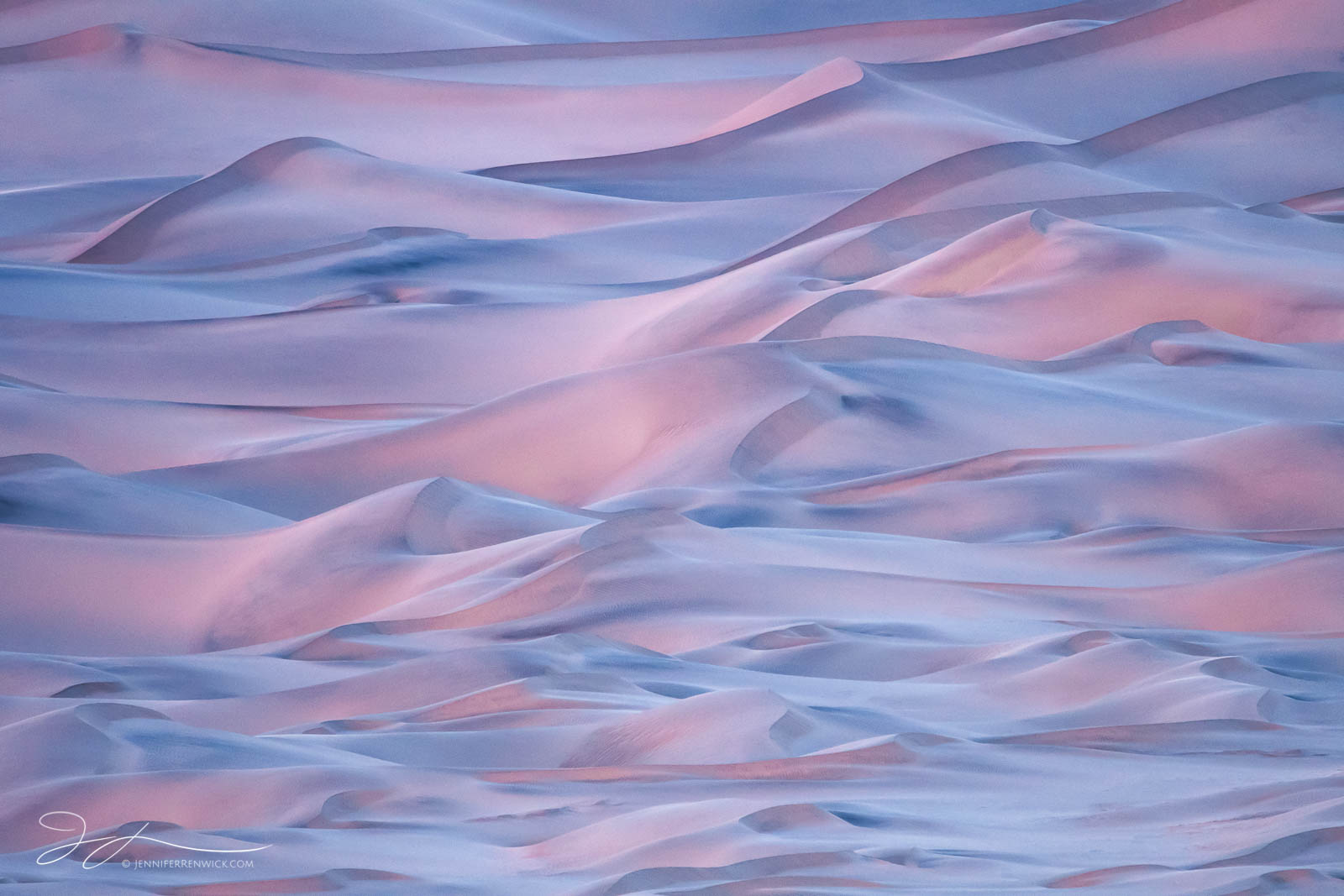 Sand dunes in Death Valley reflect pink from the sky after sunset.