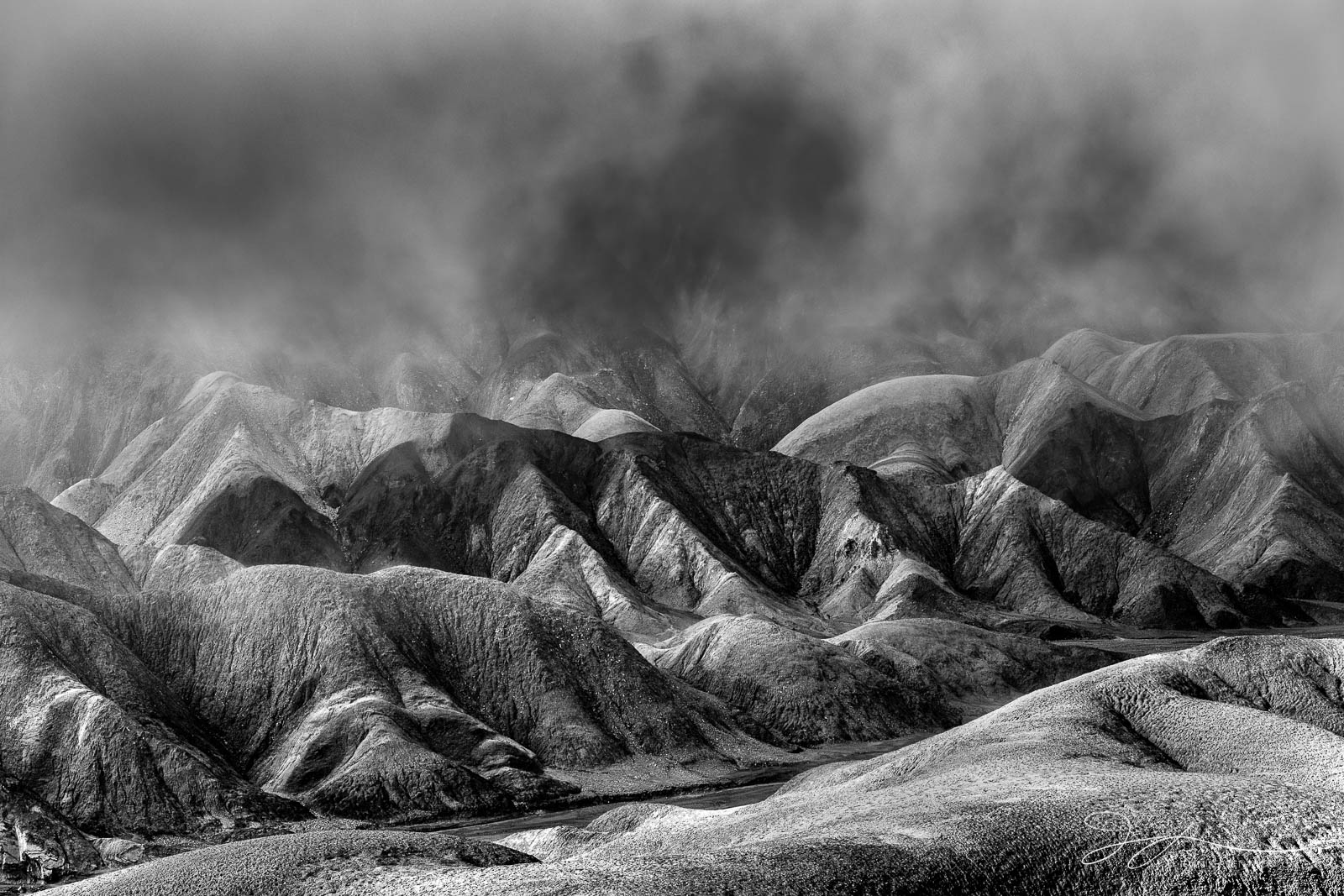 Sun breaks through and clears the fog after a rainy night in the badlands of Death Valley National Park.  This image is part...