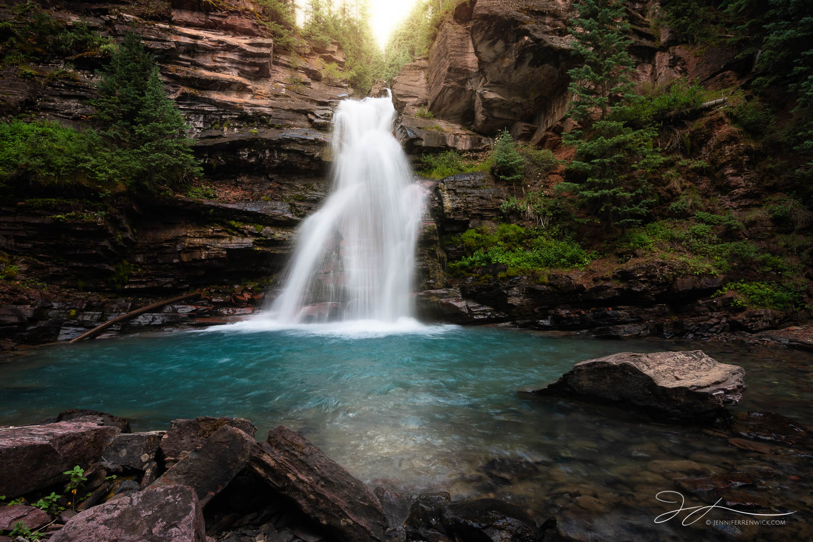 A waterfall deep in the Colorado wilderness glows in the late afternoon light.