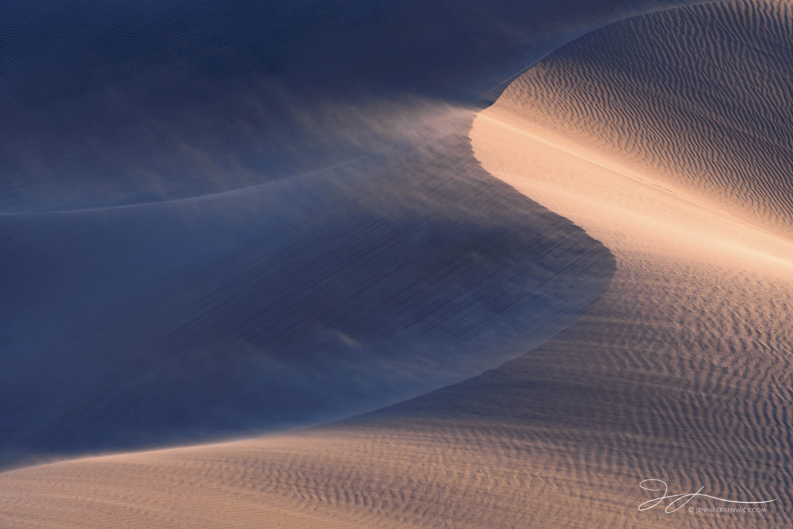 An illuminated dune glows during a late afternoon windstorm.